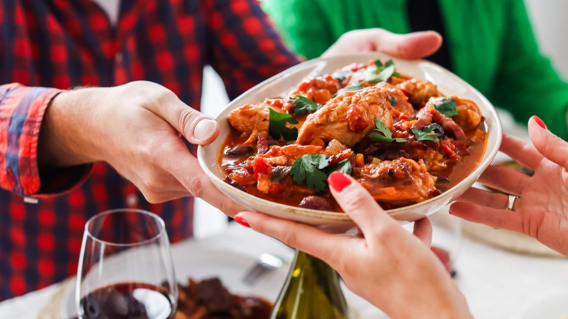A bowl of chicken cacciatore being passed at the table
