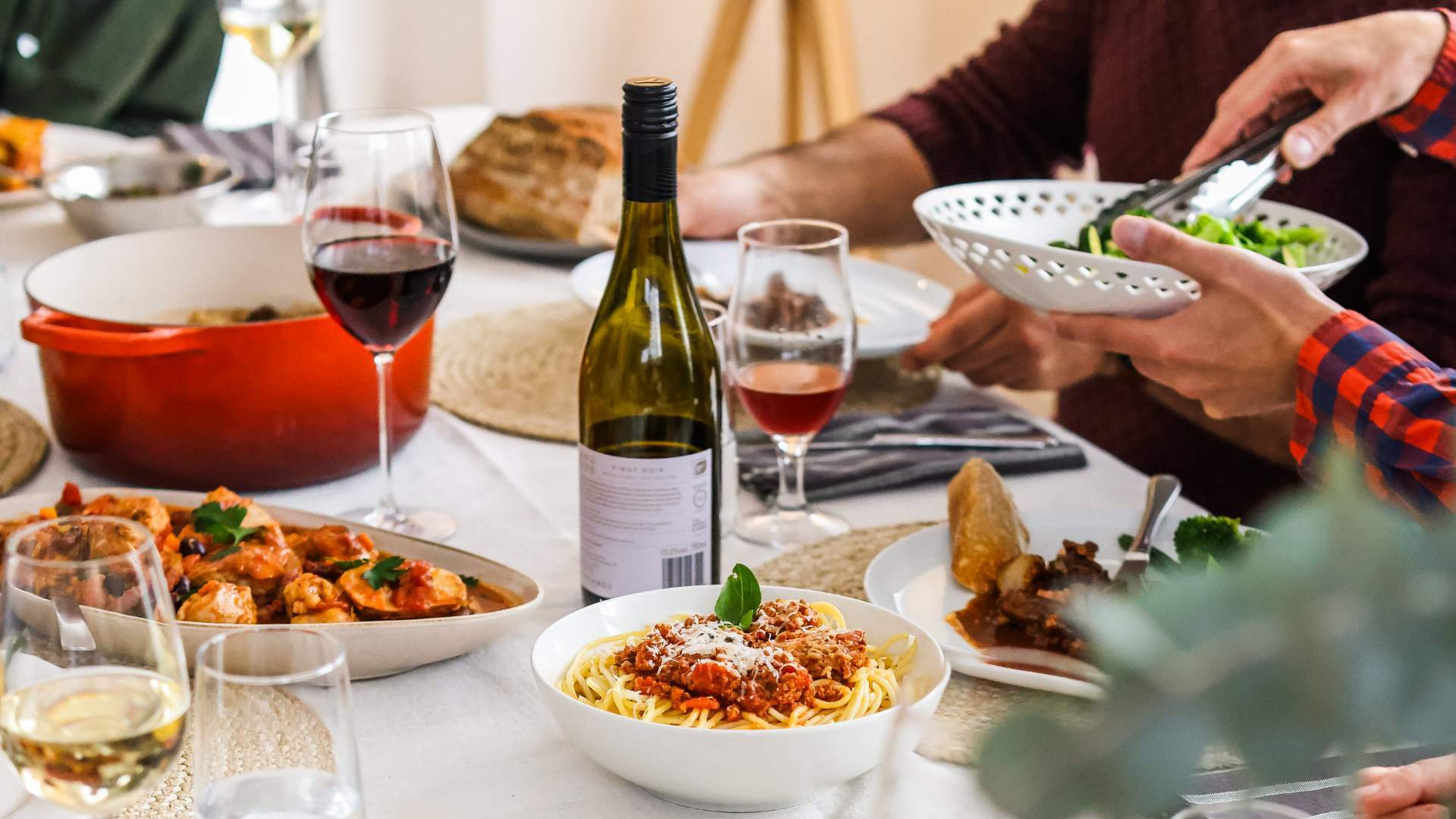 A relaxed table set with wine, pasta and friends